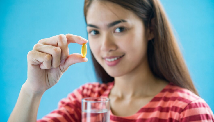 Mujer sosteniendo con los dedos una pastilla de biotina